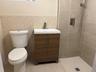 Full bathroom featuring a stall shower, tile walls, vanity, light tile patterned floors, and a wainscoted wall