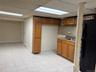 Kitchen with freestanding refrigerator, brown cabinetry, tasteful backsplash, light tile patterned floors, and dark stone countertops