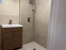 Bathroom with vanity, a shower stall, and tile walls