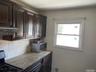 Kitchen featuring range, light stone counters, dark brown cabinetry, stainless steel microwave, and decorative backsplash
