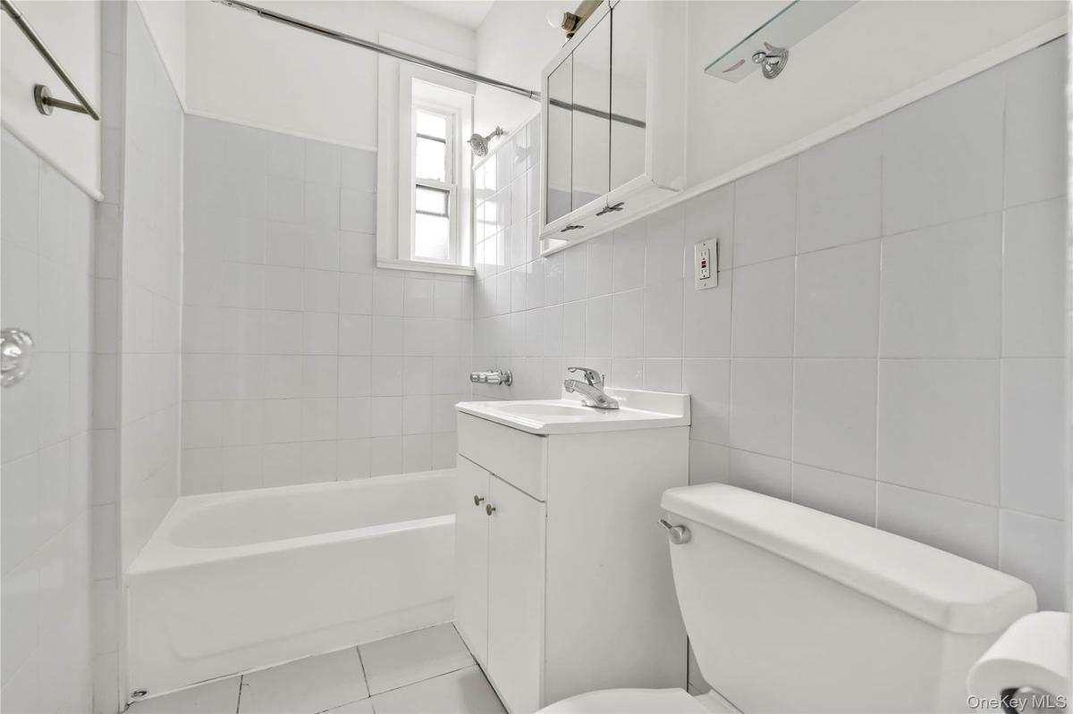 Bathroom featuring vanity, shower / tub combination, tile walls, and light tile patterned flooring