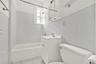 Bathroom featuring vanity, shower / tub combination, tile walls, and light tile patterned flooring