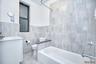 Full bath with tile walls, vanity, shower / bathtub combination, and a wainscoted wall