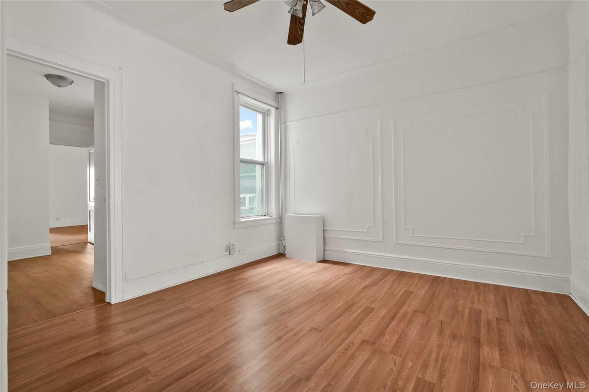 Spare room with light wood-type flooring, ceiling fan, and a decorative wall