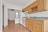 Kitchen featuring white range with gas cooktop, decorative backsplash, light wood-style flooring, under cabinet range hood, and a ceiling fan