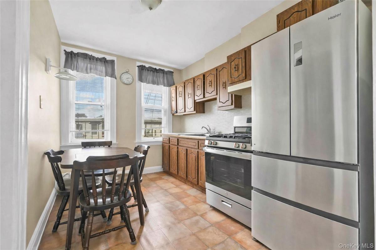 Kitchen with stainless steel appliances, light countertops, decorative backsplash, brown cabinetry, and under cabinet range hood
