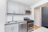 Kitchen with stainless steel appliances, backsplash, and light stone counters