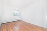 Empty room with light wood-style floors and a baseboard heating unit
