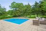 View of pool with a patio area and view of wooded area