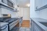 Kitchen with appliances with stainless steel finishes, tasteful backsplash, light wood finished floors, and light stone counters