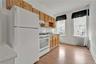 Kitchen featuring white appliances, radiator heating unit, tasteful backsplash, under cabinet range hood, and light wood-type flooring