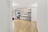 Kitchen with appliances with stainless steel finishes, light wood finished floors, dark countertops, tasteful backsplash, and track lighting
