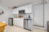 Kitchen featuring light countertops, appliances with stainless steel finishes, white cabinetry, decorative backsplash, and concrete flooring