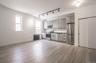 Kitchen with appliances with stainless steel finishes, radiator, rail lighting, gray cabinets, and light wood-type flooring