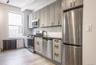 Kitchen featuring stainless steel appliances, radiator heating unit, gray cabinetry, light wood-style floors, and backsplash