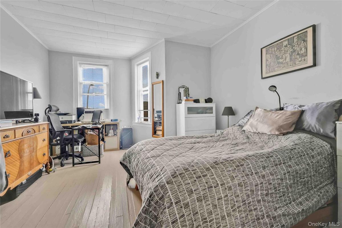 Bedroom featuring a desk, crown molding, and light wood-style flooring