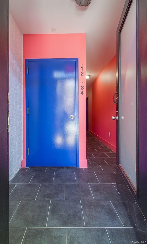 Corridor with brick wall and dark tile patterned floors