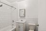 Bathroom with vanity, shower / bath combination, tile walls, and wainscoting