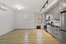 Kitchen with appliances with stainless steel finishes, gray cabinets, radiator heating unit, backsplash, and a wall unit AC