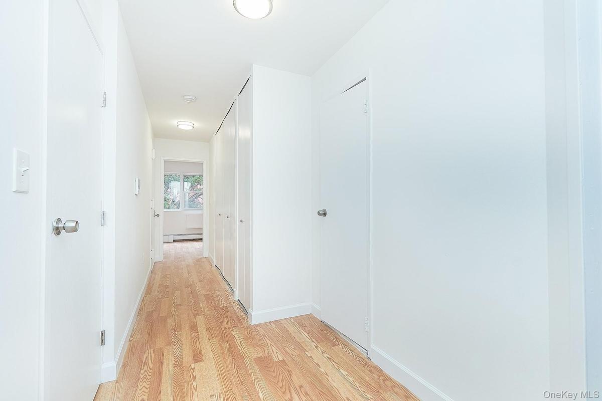 Hallway with light wood-style flooring and a baseboard radiator