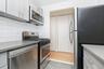 Kitchen featuring stainless steel appliances, tasteful backsplash, gray cabinets, light tile patterned floors, and light stone counters