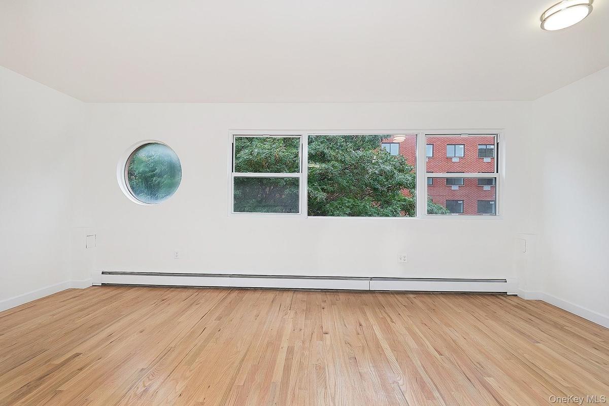 Spare room featuring healthy amount of natural light, light wood finished floors, and a baseboard radiator