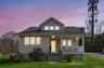 Bungalow-style house featuring covered porch, a front yard, and roof with shingles