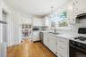 Kitchen featuring backsplash, appliances with stainless steel finishes, white cabinetry, and tile countertops