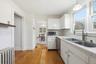 Kitchen with white cabinetry, light wood-style floors, tasteful backsplash, and tile countertops