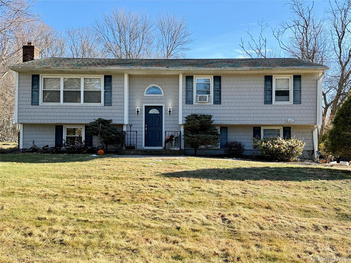 Bi-level home featuring a front lawn and a chimney