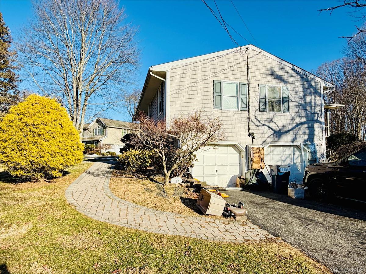 View of side of property featuring asphalt driveway, a garage, and a yard