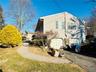 View of side of property featuring asphalt driveway, a garage, and a yard