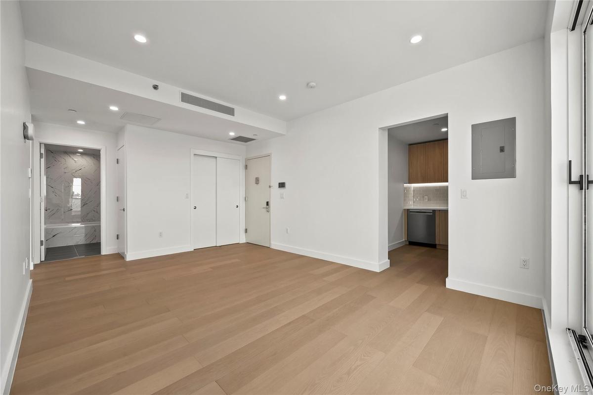 Unfurnished bedroom featuring connected bathroom, light wood finished floors, recessed lighting, and electric panel