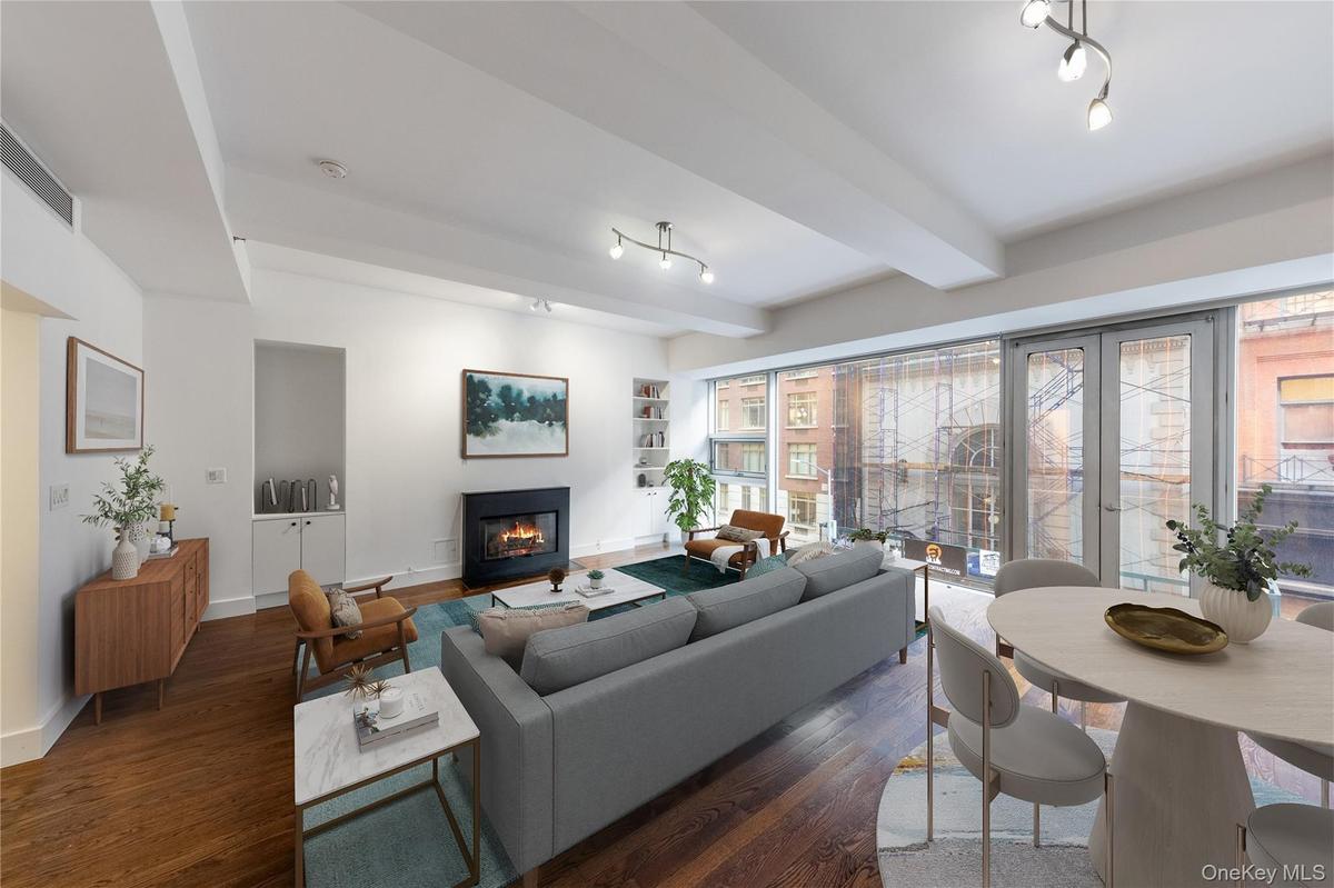 Living area featuring beam ceiling, dark wood-type flooring, a glass covered fireplace, and built in features