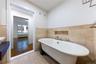 Bathroom with a freestanding tub, tile walls, tile patterned floors, and a wainscoted wall
