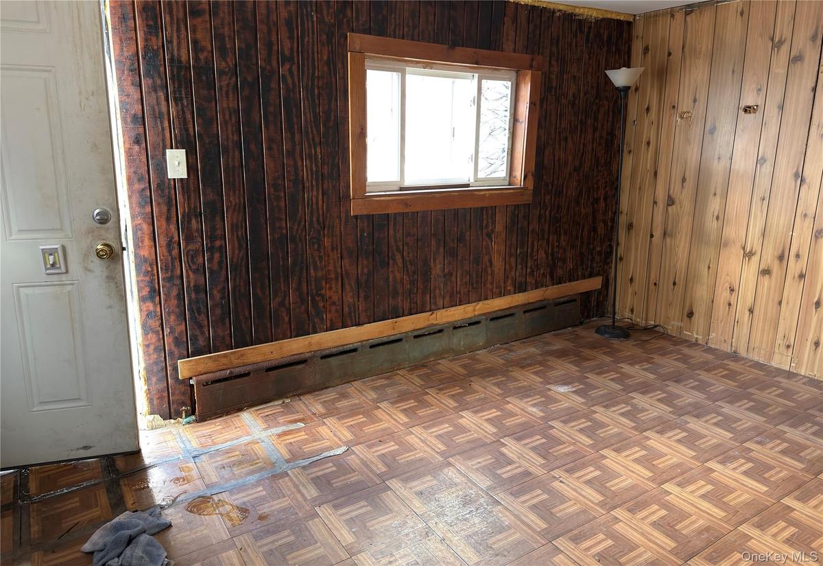 Empty room with a baseboard radiator and wooden walls