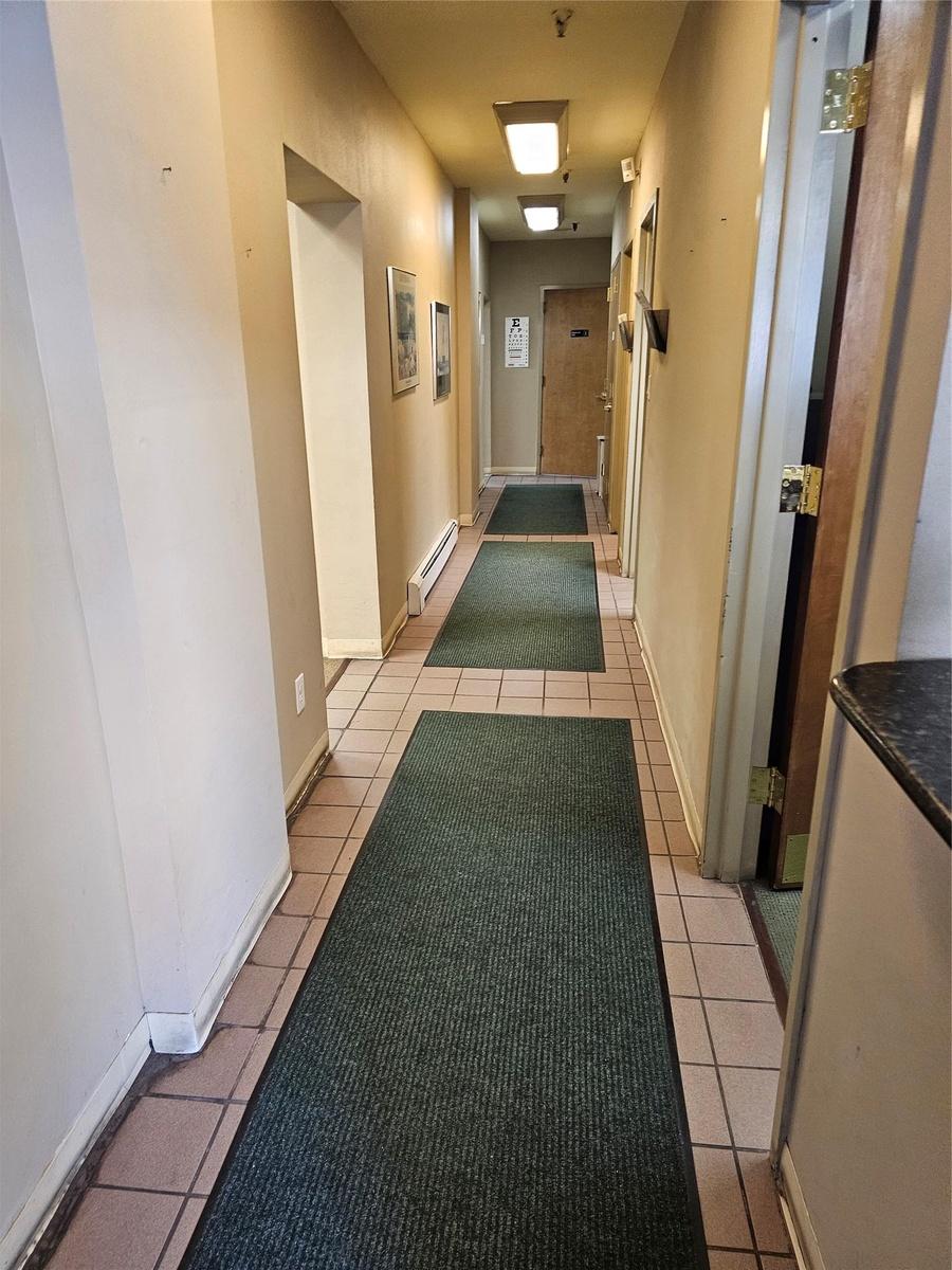 Corridor with light tile patterned floors and a baseboard heating unit
