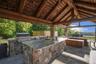 Custom outdoor kitchen pavilion with hot and cold water, Lynx appliances, refrigerator, storage and beautiful seating areas. An outdoor shower is loca