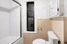 Full bathroom with tile walls, bath / shower combo with glass door, and a wainscoted wall