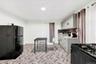 Kitchen with black appliances, gray cabinets, light stone counters, backsplash, and recessed lighting