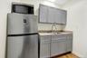 Kitchen with gray cabinets, stainless steel appliances, light wood-style floors, and light stone countertops
