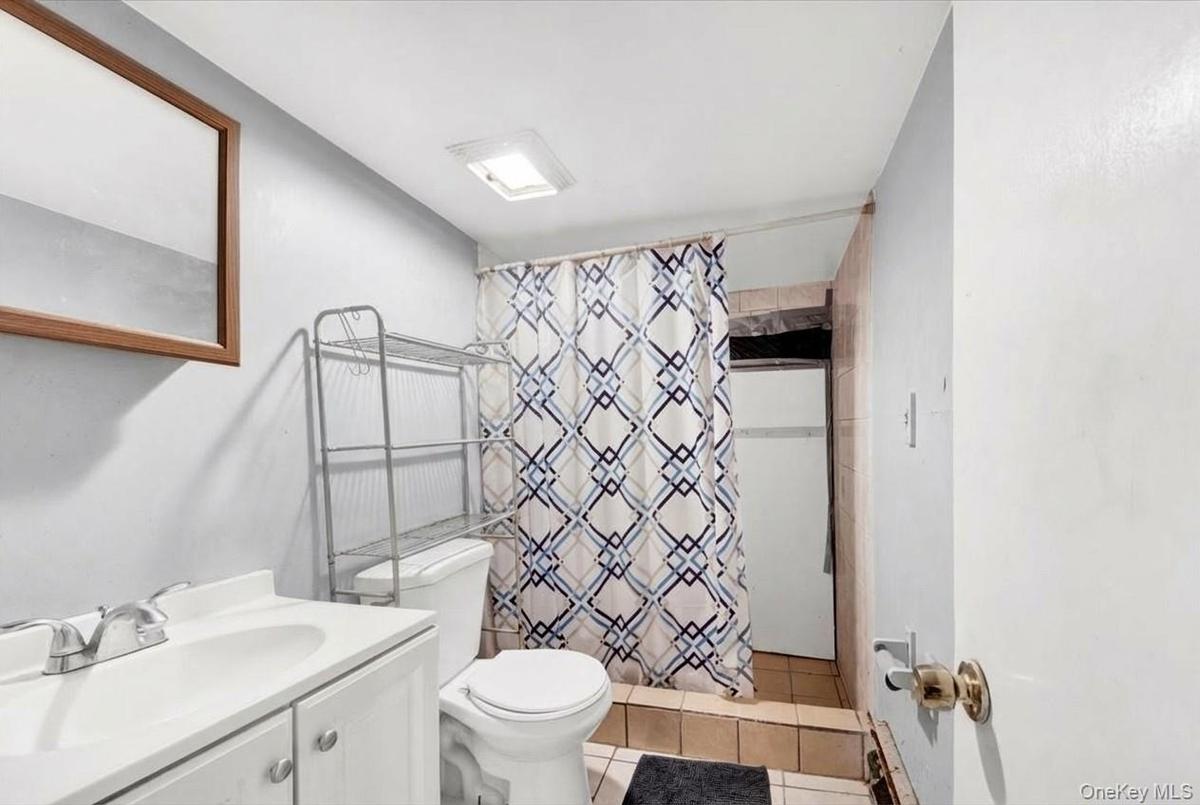 Full bathroom featuring curtained shower, vanity, and light tile patterned floors