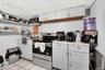 Kitchen with stainless steel electric stove, white cabinets, open shelves, light tile patterned floors, and black microwave