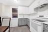 Kitchen featuring white appliances, gray cabinets, under cabinet range hood, and white cabinets
