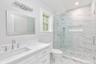 Bathroom featuring vanity, a marble finish shower, marble finish floors, and vaulted ceiling