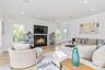 Living area with a fireplace with flush hearth, wood finished floors, recessed lighting, and ornamental molding