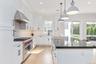 Kitchen featuring dark stone countertops, double oven range, decorative light fixtures, white cabinets, and ornamental molding