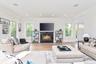 Living room featuring a glass covered fireplace, light wood finished floors, healthy amount of natural light, crown molding, and recessed lighting