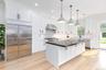 Kitchen with appliances with stainless steel finishes, white cabinetry, crown molding, pendant lighting, and light wood finished floors