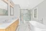 Full bath featuring double vanity, a soaking tub, light marble finish flooring, a marble finish shower, and recessed lighting